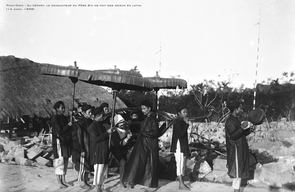 Viên quan người Pháp tuần du Phát Diệm trên võng, xung quanh có người quạt và che dù. Ảnh: André Salles.