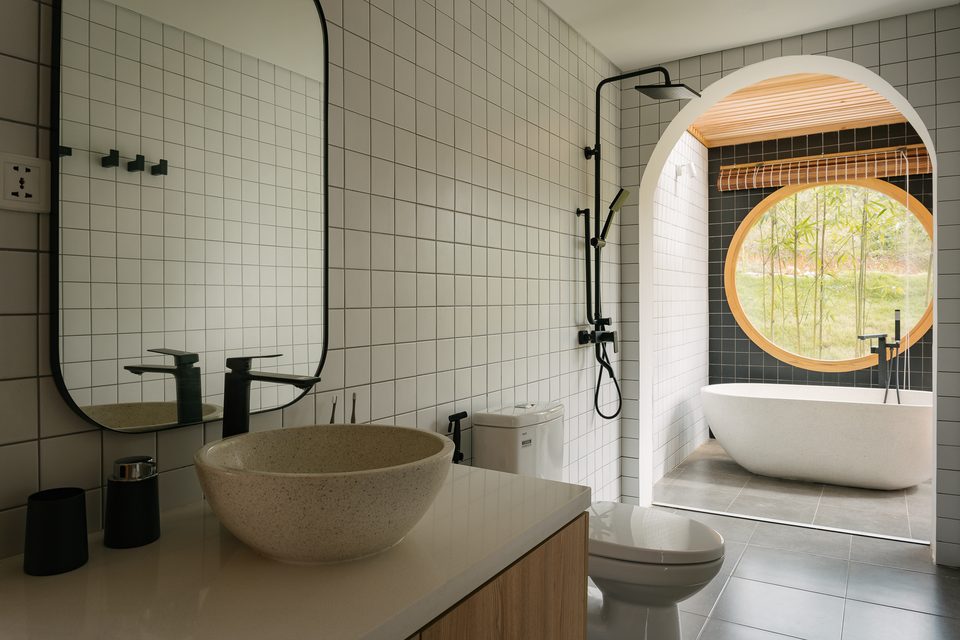 br/> Toilet tầng 1 sử dụng bồn tắm chất liệu granite, tường và sàn được ốp gạch ngăn nắp. Để tối ưu ánh sáng trời, khu vực bồn tắm sử dụng rèm mành dân dã, kết hợp mái kính rào gỗ.