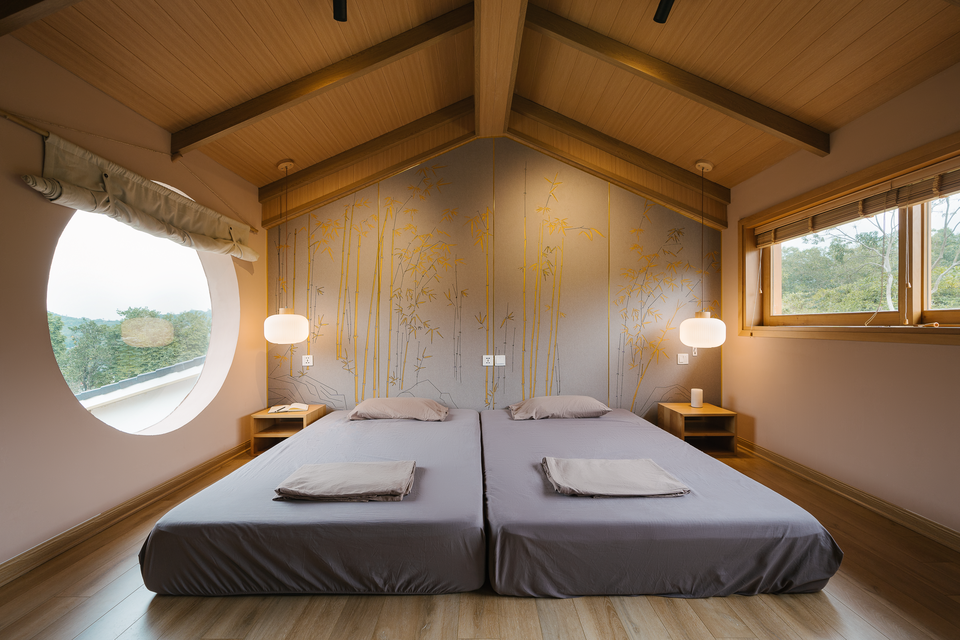 br/> Tầng trên gồm một phòng ngủ và vệ sinh khép kín. Đầu giường làm bằng gỗ công nghiệp vân vải, khắc và sơn thủ công lá trúc. Cây trúc có ý nghĩa tốt đẹp. Theo phong thủy, việc trúc mọc trước và sau nhà sẽ đem lại điều tốt lành cho cả gia đình. Loại cây này còn tượng trưng cho sự tinh tế, mảnh mai.