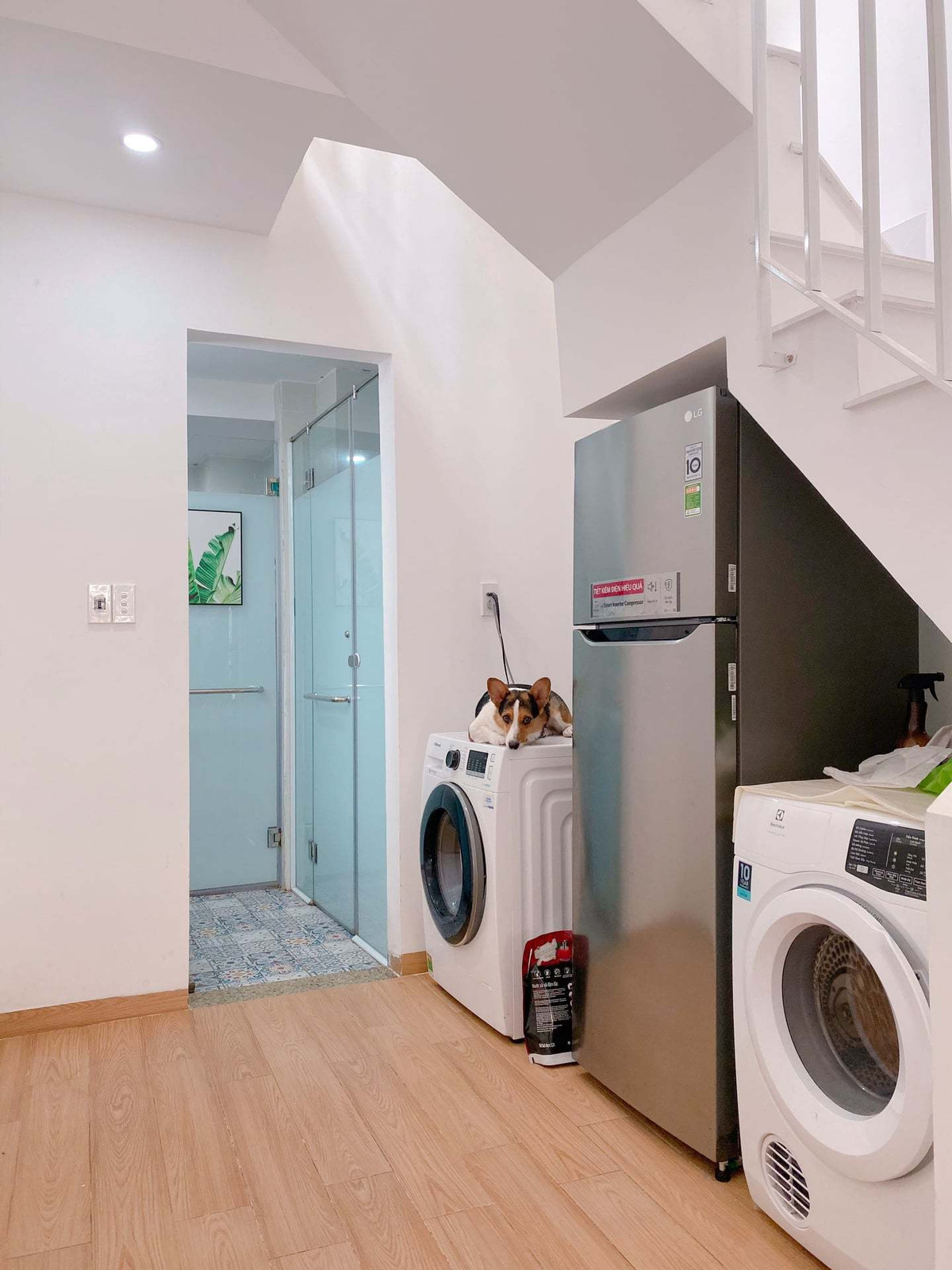 Khu vực sảnh lên cầu thang được tận dụng làm chỗ kê bàn ăn, còn gầm cầu thang thiết kế máy giặt sấy, tủ lạnh để tiết kiệm diện tích. Phía trong là nhà tắm và vệ sinh.