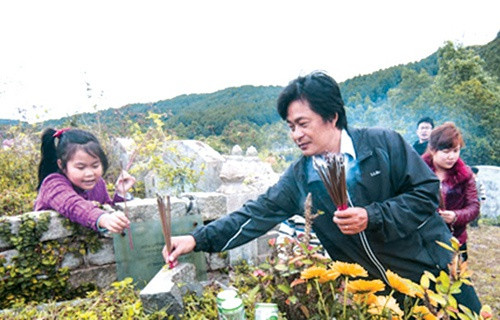 Chiều 30 Tết được cha dẫn đi tảo mộ là kỷ niệm khó quên của Phạm Thủy (21 tuổi, quê Nam Định). "Mỗi năm một lần, hai cha con lại dọn dẹp, thắp hương tại mộ các cụ. Cái Tết xưa dù khó khăn, vẫn luôn toát lên niềm vui và giàu giá trị truyền thống", Thủy nói. Ảnh: Báo Quảng Nam.