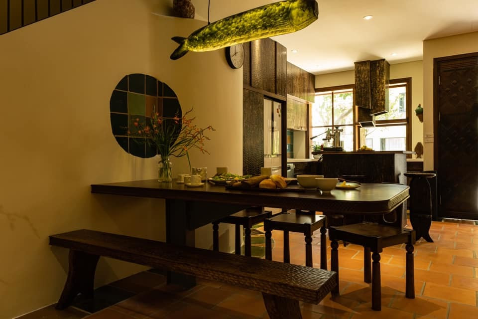 Bàn ăn chỉ có 1 chân trụ to, chắc, găm sâu xuống nền nhà. Cách làm này giúp khi ngồi mọi người không bị vướng víu chân bàn. Đèn con cá nghệ thuật, mang phong cách Nhật.