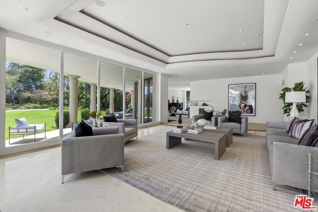 Phòng khách rộng lớn, thoáng đãng, nổi bật với bức tường kính đem đến ánh sáng tự nhiên và mở ra không gian sân vườn.