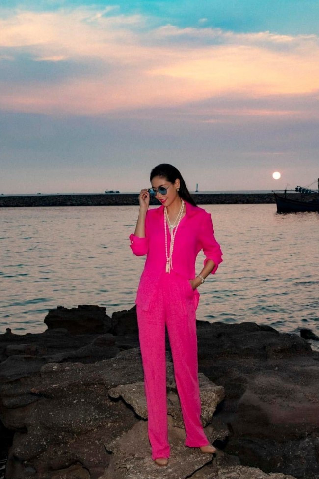 Hà Kiều Anh nổi bật dưới ánh hoàng hôn bên bờ biển trong set đồ màu hồng đậm, gồm áo sơ mi và quần âu. Nữ diễn viên phim “Hạnh phúc có thật” phối cùng bộ phụ kiện ngọc trai và mắt kính màu xanh nước biển, tạo nên vẻ ngoài vừa thời thượng vừa phóng khoáng.