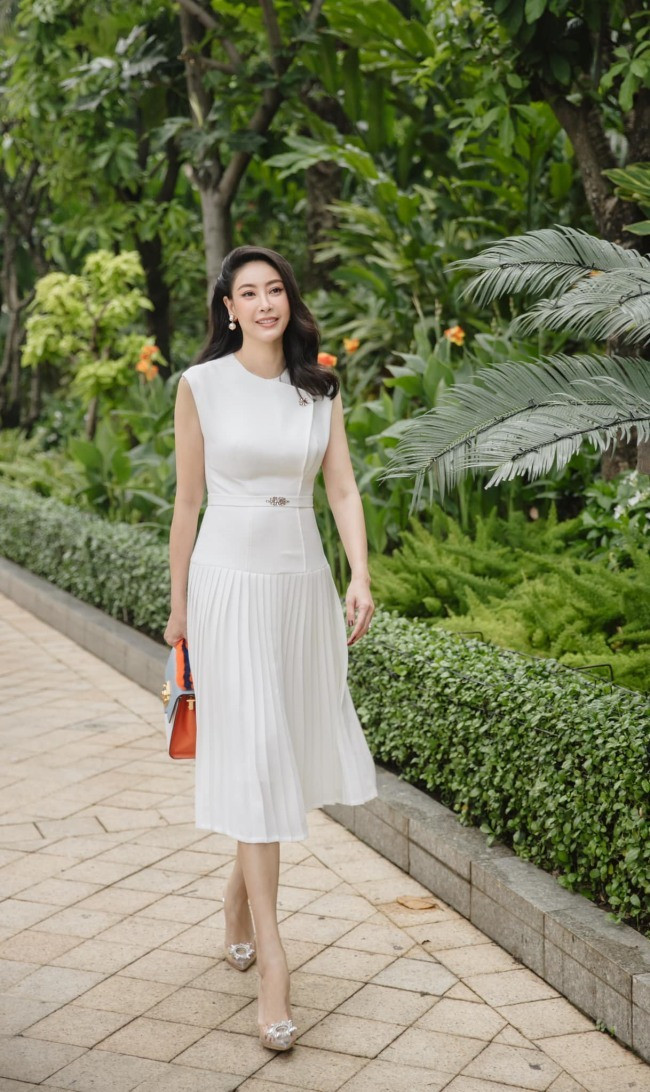 Hà Kiều Anh trẻ trung trong chiếc váy trắng với phần thân trên bó sát và chân váy xếp ly, tóc xõa nhẹ nhàng kết hợp cùng bông tai ngọc trai.