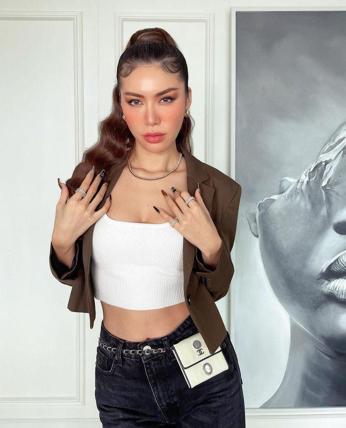 inh Tú mặc áo hai dây crop-top, mix cùng áo blazer bên ngoài, phối thêm phụ kiện túi đeo hông Chanel đắt đỏ.