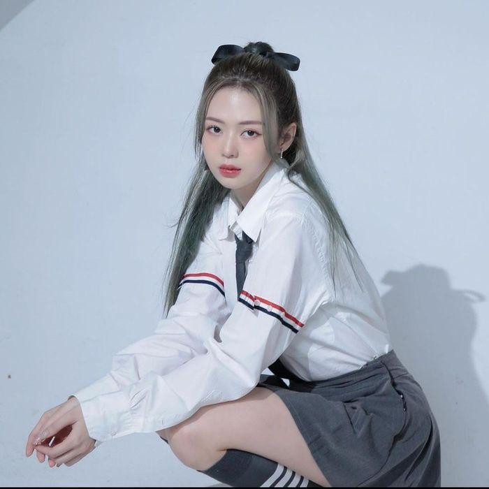 iz Kim Cương lăng-xê style nữ sinh hack tuổi với áo sơ mi trắng cùng chân váy tennis màu xám, đeo cà vạt.