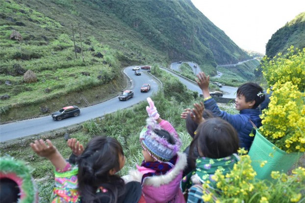 Các bạn nhỏ với gùi hoa cải vàng trên lưng, cố nhún mình vẫy tay đón chào đoàn . 