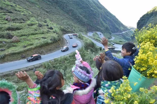 Các bạn nhỏ với gùi hoa cải vàng trên lưng, cố nhún mình vẫy tay đón chào đoàn . 