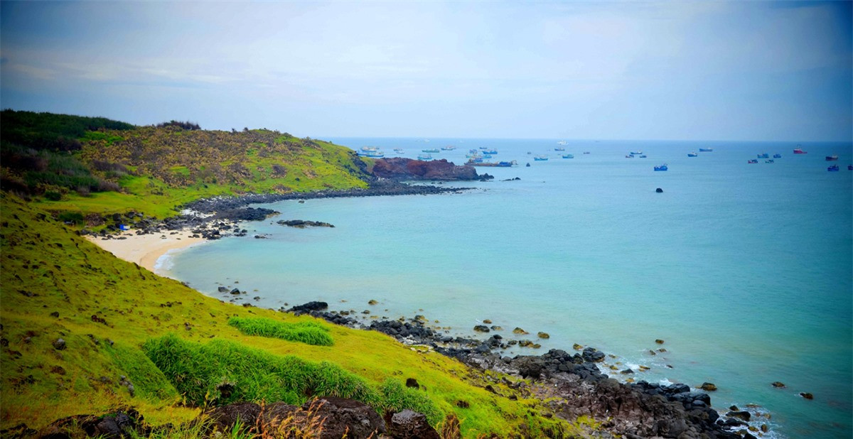 Phong cảnh từ đỉnh núi Cao Cát, khu vực cao nhất trên đảo, những vách núi đá đen xen cỏ xanh,ven bờ bãi cỏ xanh rì nhìn ra biển.