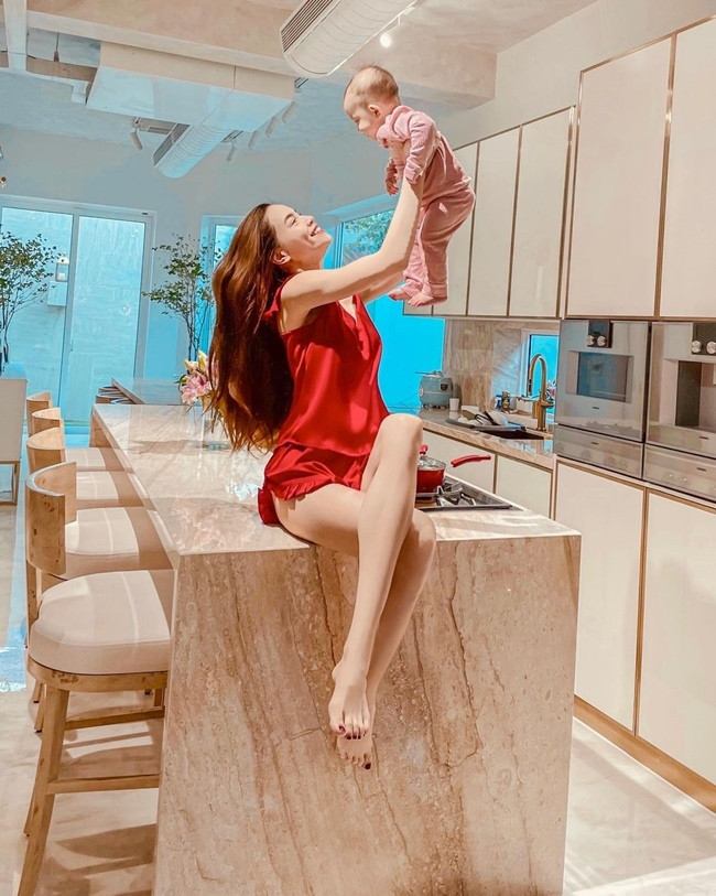 Từ ngày có cặp sinh đôi Lisa - Leon, Hà Hồ ở nhà nhiều hơn. Cô chọn bộ đồ lụa đỏ vừa sang trọng lại vừa nữ tính, khéo khoe đôi chân thon dài. Cô thả tóc xõa tự nhiên và không trang điểm cầu kỳ khi chụp ngay trong gian bếp nhà mình.