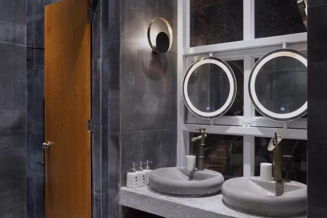 Không gian nhà tắm được trang trí thêm những chiếc đèn thả hình tròn và ô cửa thoáng rộng kết nối với bên ngoài.