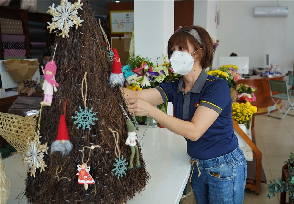 Nhân viên cửa hàng hoa tại quận 3, TPHCM tất bật trang trí cây thông cho khách. Năm nay chuỗi cửa hàng này còn có thêm sản phẩm cây thông tái chế từ lá cây, các mẫu này dao động từ 1-3 triệu đồng/cây đã trang trí hoàn chỉnh.