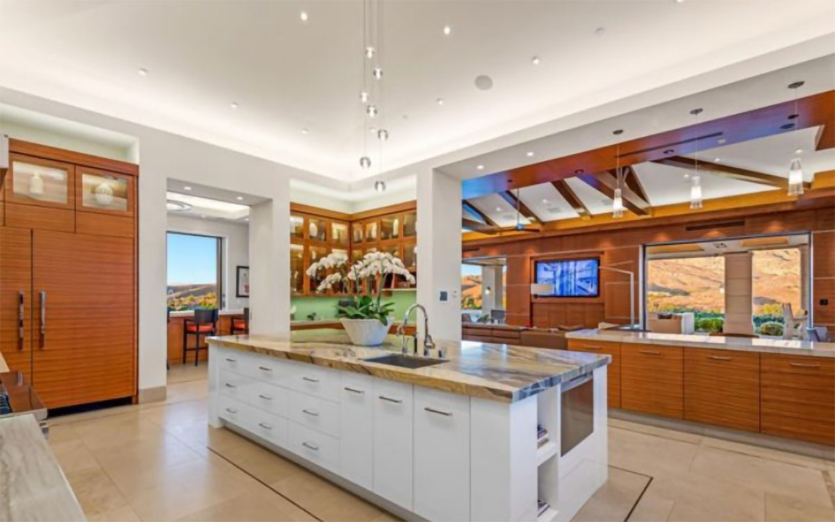 Nhà bếp rộng lớn, được trang hoàng với những nội thất sang trọng làm từ gỗ và đá cùng các thiết bị nấu nướng cao cấp.