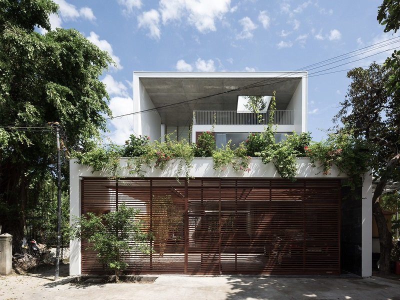 Thêm một mẫu nhà mái bằng theo phong cách hiện đại. Cổng nhà được trồng thêm cây xanh tạo độ che phủ làm dịu bớt cái nóng. 