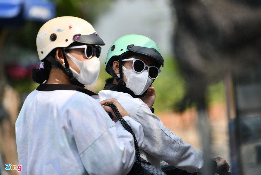 Hai nữ du khách đeo khẩu trang kháng khuẩn tham quan đường hoa bằng xe máy. Họ di chuyển khá nhanh trên đường chính, không ghé vào các vườn chụp ảnh hay mua hoa kiểng.