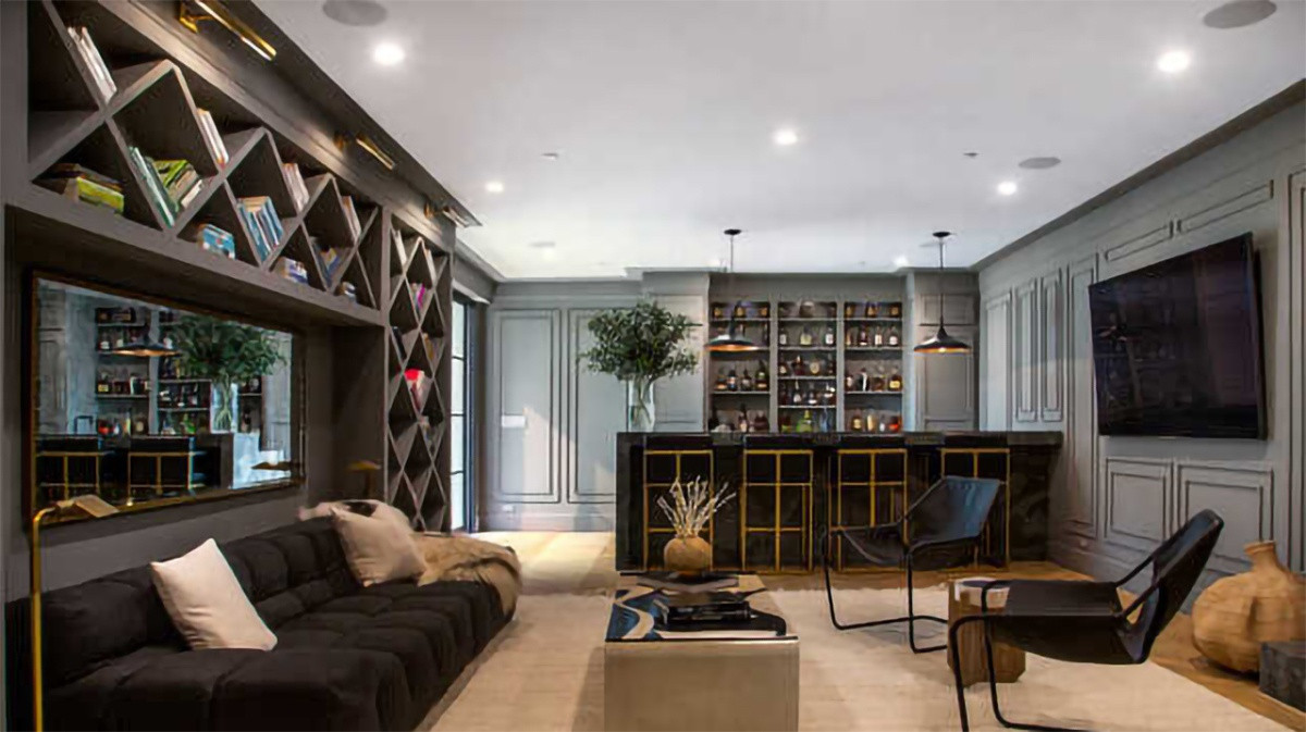 Một khu vực tiếp khách khác mang tông màu tối, có điểm nhấn là kệ sách cầu kỳ cùng một quầy bar nhỏ nhắn, sang trọng.