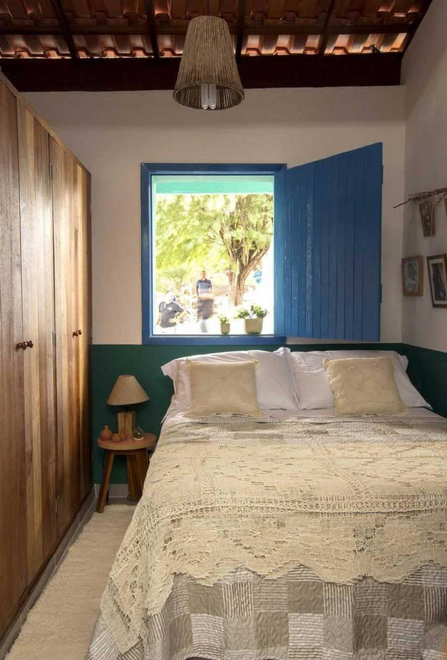 Phòng ngủ có cửa sổ lớn sơn màu xanh dương đậm, tủ đứng và giường đều kê sát tường để mọi thứ trông rộng rãi và gọn gàng nhất có thể. 