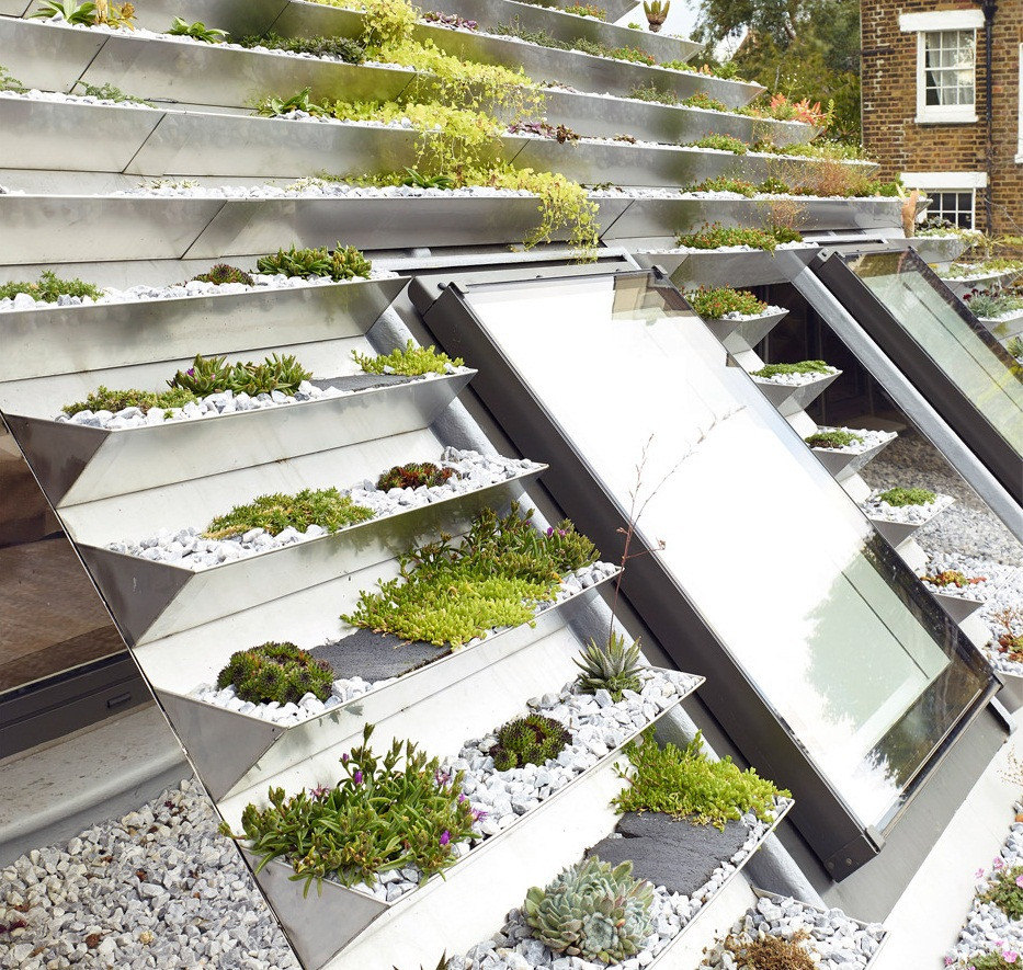 Nhằm tạo ra khu vườn, các kiến trúc sư đã gắn một loạt khay thép không gỉ lên mái nhà nghiêng 30 và 45 độ. Các cây được trồng vào trong khay, xung quanh rải đá cuội... Khu vườn không quá rộng nhưng các cây trồng nho nhỏ giúp gia chủ có một không gian đẹp mắt giữa phố thị đông đúc nhà cửa.