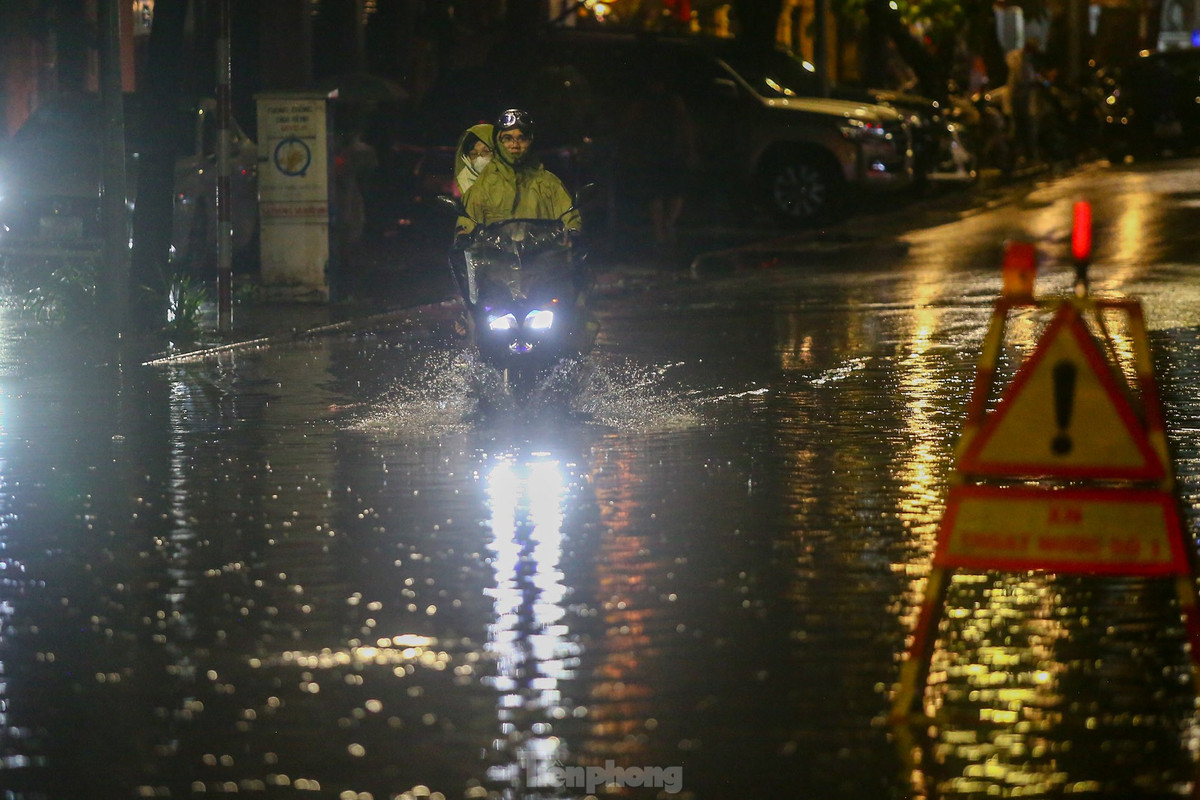 Khoảng 21h ngày 8/6, nước vẫn chưa rút hết trên phố; các phương tiện chỉ có thể di chuyển chậm qua khu vực bị ngập.