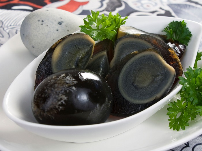 2. Trứng thế kỷ: Trứng thế kỷ là một trong những món ăn truyền thống lâu đời ở Trung Quốc. Món ăn này có màu đen khá kì dị, không phải du khách nào cũng dám ăn thử khi nhìn thấy chúng. Có 2 cách để làm ra loại trứng này đó là phương pháp truyền thống và phương pháp hiện đại. Với phương pháp truyền thống, trứng sẽ được ủ trong đất sét khoảng 10 ngày. Còn đối với phương pháp hiện đại, trứng sẽ được ngâm trong dung dịch hóa chất. Cả hai phương pháp đều khiến protein albumen biến tính trong điều kiện kiềm, từ đó tạo ra trứng thế kỷ. Tuy nhiên, nhiều ý kiến cho rằng, khoảng thời gian 10 ngày của phương pháp truyền thống không đủ để bảo quản trứng, khiến trứng dễ bị hỏng hơn phương pháp hiện đại.