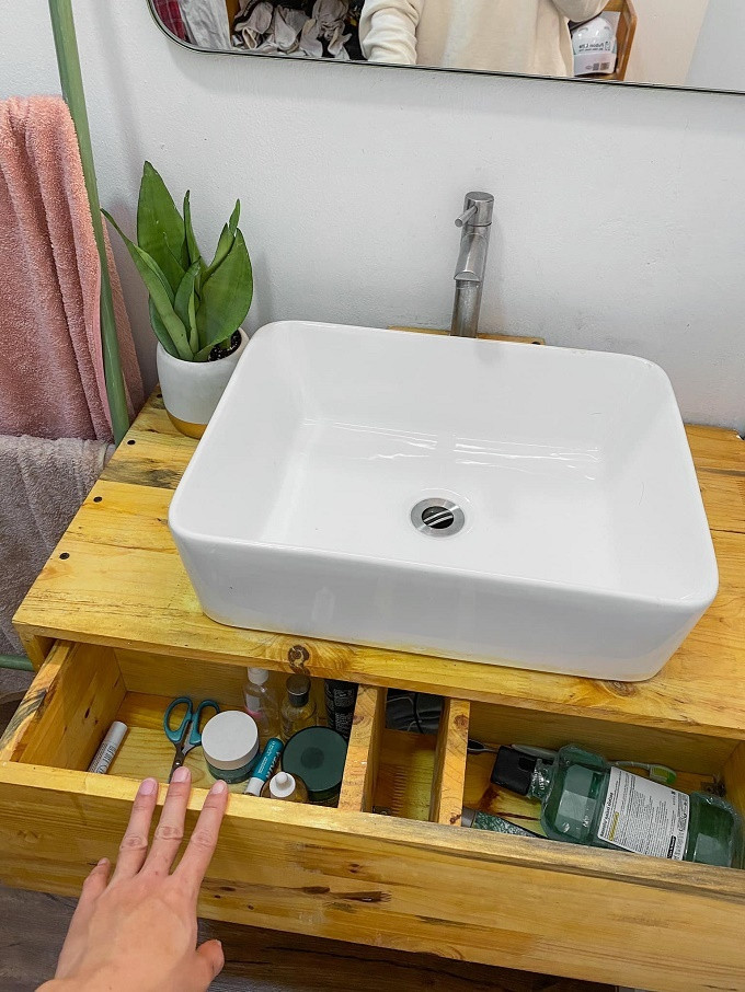 Tủ gỗ bồn rửa mặt có ngăn kéo để đồ cho gọn, một bên đựng đồ chăm sóc da, một bên chứa bàn chải.