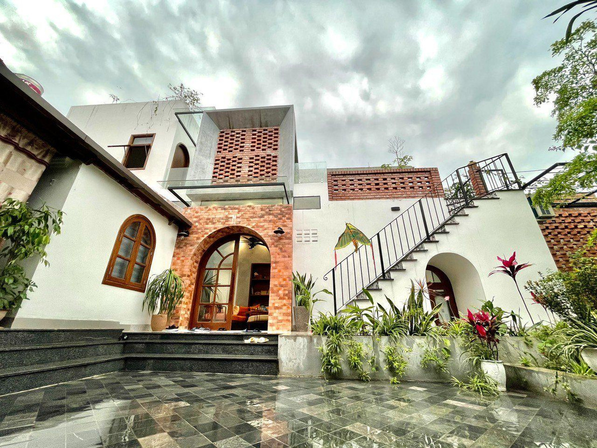 Cửa vào nhà xây gạch đỏ, mái vòm với mái hiên kính cản mưa hắt. Nhóm thiết kế đã cố gắng đưa thật nhiều ánh sáng và gió mát vào nhà thông qua tường gạch lỗ, cửa kính, giếng trời...