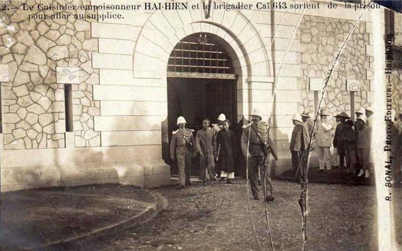 Đầu bếp Hai Hiên (mặc áo dài đen) và đồng phạm trong vụ Hà Thành đầu độc đang rời nhà tù Hỏa Lò để đến nơi hành hình, 6/8/1908. Ảnh: Manhhai / Flickr.