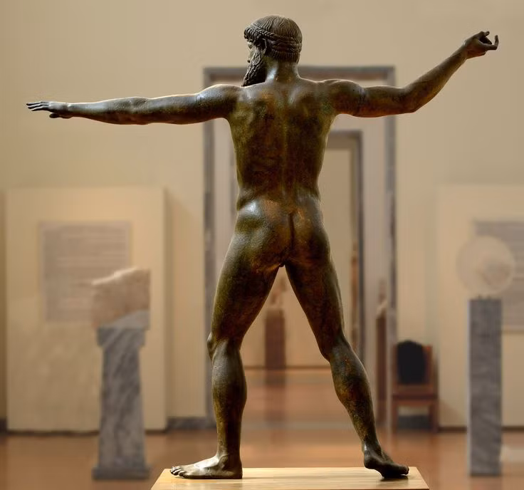  "Zeus or Poseidon of Artemision". Đây là một bức tượng đồng to lớn mô tả một vị thần (có thể là Zeus hoặc Poseidon) trong tư thế chuẩn bị ném một tia sét hoặc cây đinh ba, đầy uy nghi và mạnh mẽ. Ảnh: Pinterest.