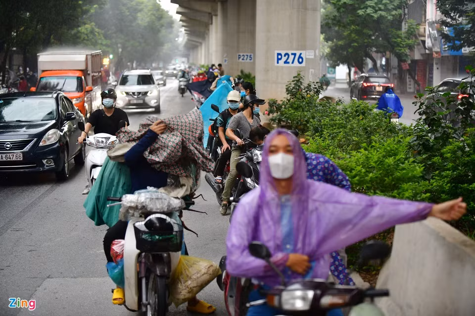 7h35 là thời điểm mưa lớn ở khu vực quận Cầu Giấy. Trên đường Xuân Thủy, nhiều người đi xe máy tạt vào trú và mặc áo mưa dưới đường tàu trên cao tuyến Nhổn - ga Hà Nội. Ảnh: Nhật Sinh.