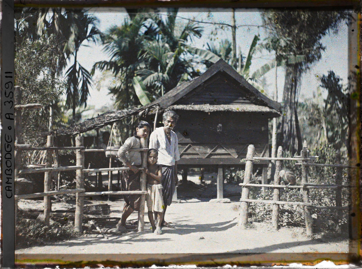 Một cụ ông, một phụ nữ trẻ và một đứa trẻ trước một ngôi nhà sàn, dạng kiến trúc phổ biến ở vùng nông thôn Siem Reap.