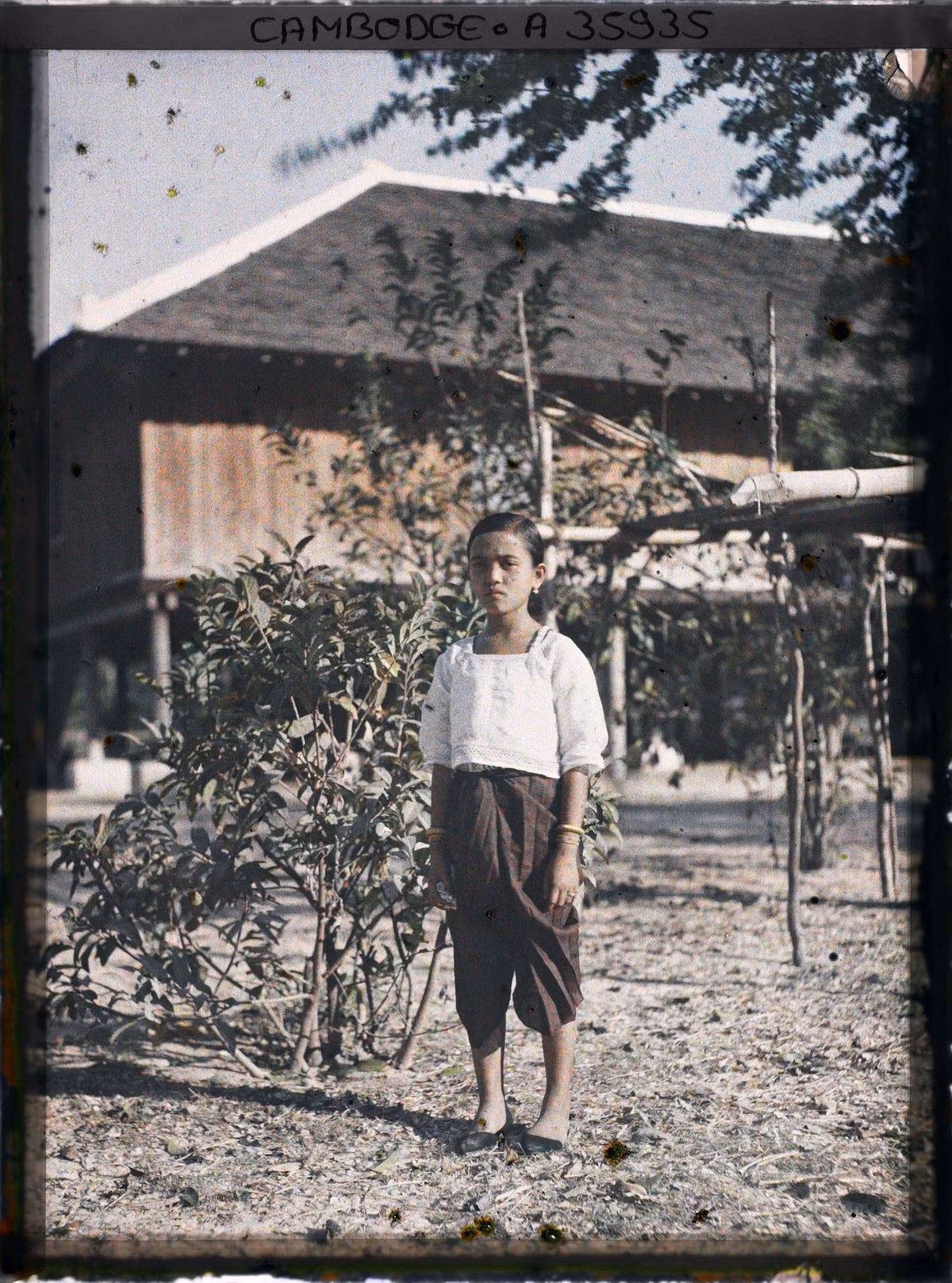 Một bé gái đứng trên sân nhà.