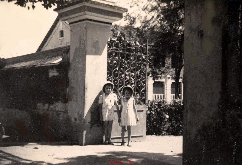 Hai học sinh nhỏ tuổi người Pháp đứng trước cổng trường Jeanne d'Arc, nay là Trường THPT Nguyễn Trường Tộ.