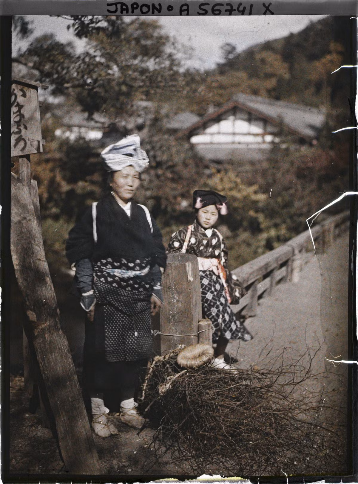 Người phụ nữ và bé gái làng Yase đứng bên cây cầu gỗ.