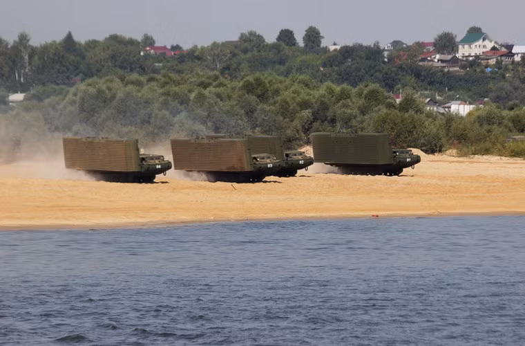 Ngoài việc di chuyển bằng cầu phao, một số khí tài cơ giới hạng nặng sẽ được di chuyển bằng phà tự hành. Trong ảnh là các xe xích đang tiến tới mép nước để thiết lập phà.