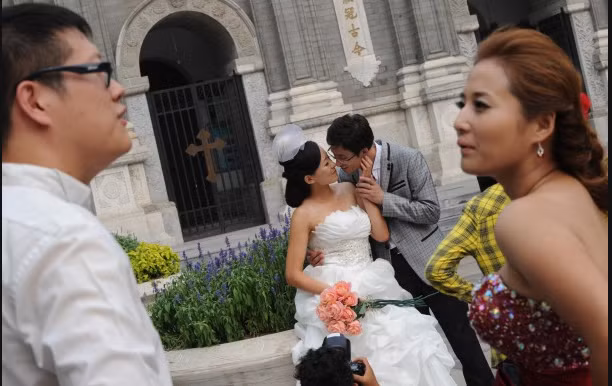 Một cặp vợ chồng giàu có của Trung Quốc chụp hình đám cưới bên ngoài Giáo Hội Vương Phủ Tỉnh Bắc Kinh.