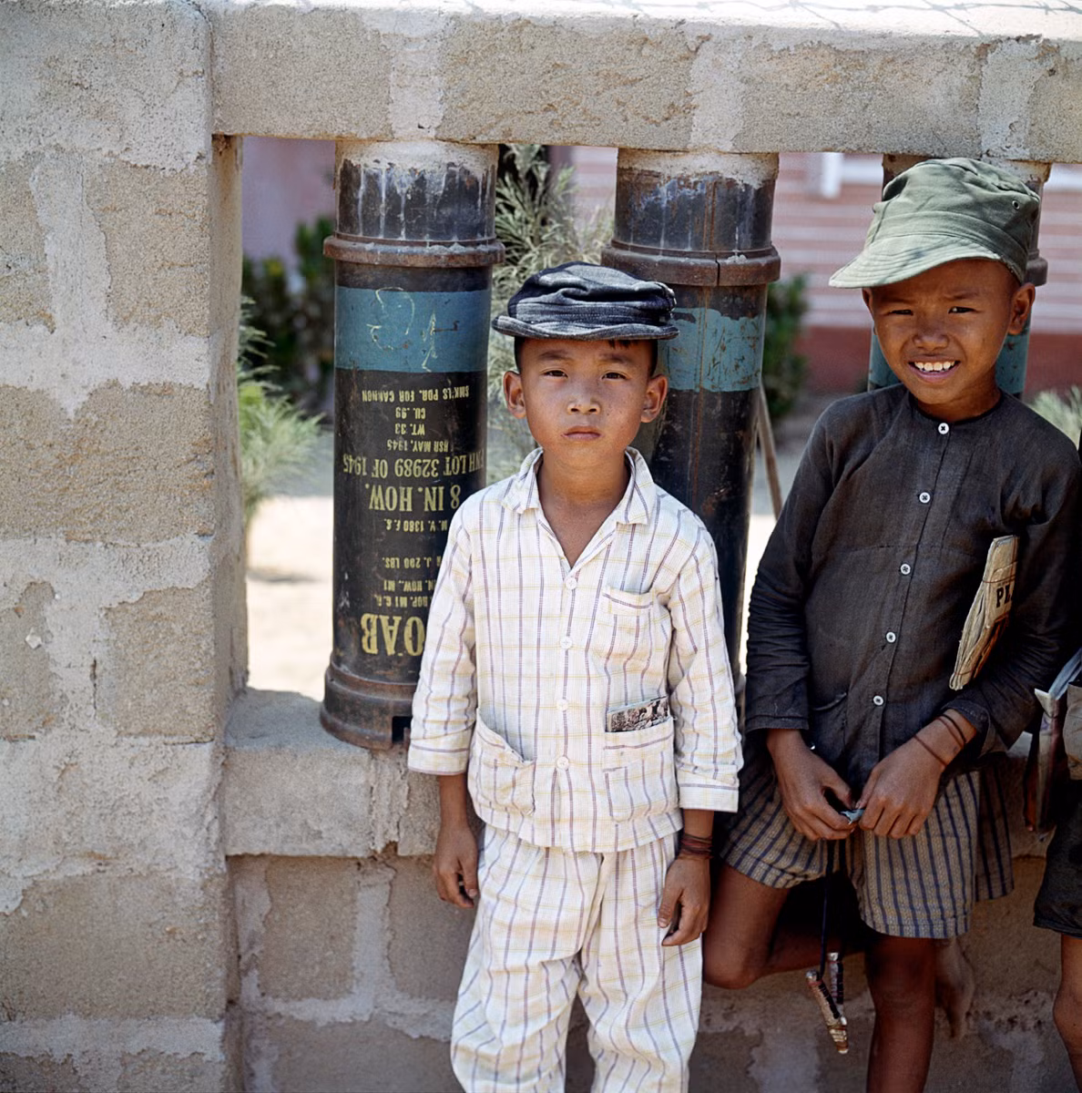 Hai cậu bé đứng cạnh một bức tường được dựng bằng vỏ bình xăng Mỹ. Ảnh: Geheugenvannederland.nl