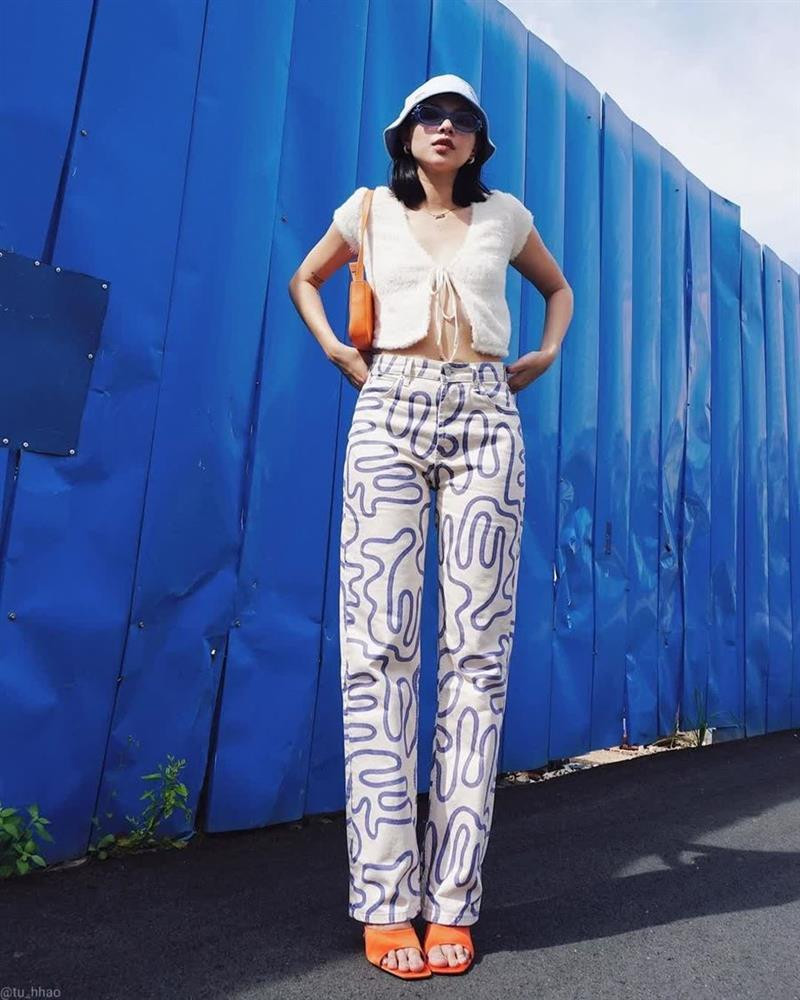 Tú Hảo khoe khéo eo thon cùng phong cách thời thượng khi diện crop top cùng quần họa tiết ống rộng. Để hoàn thiện vẻ cá tính cho set đồ đường phố, cô nàng sử dụng bộ đôi phụ kiện túi xách và giày cao gót tiệp màu cam nổi bật.