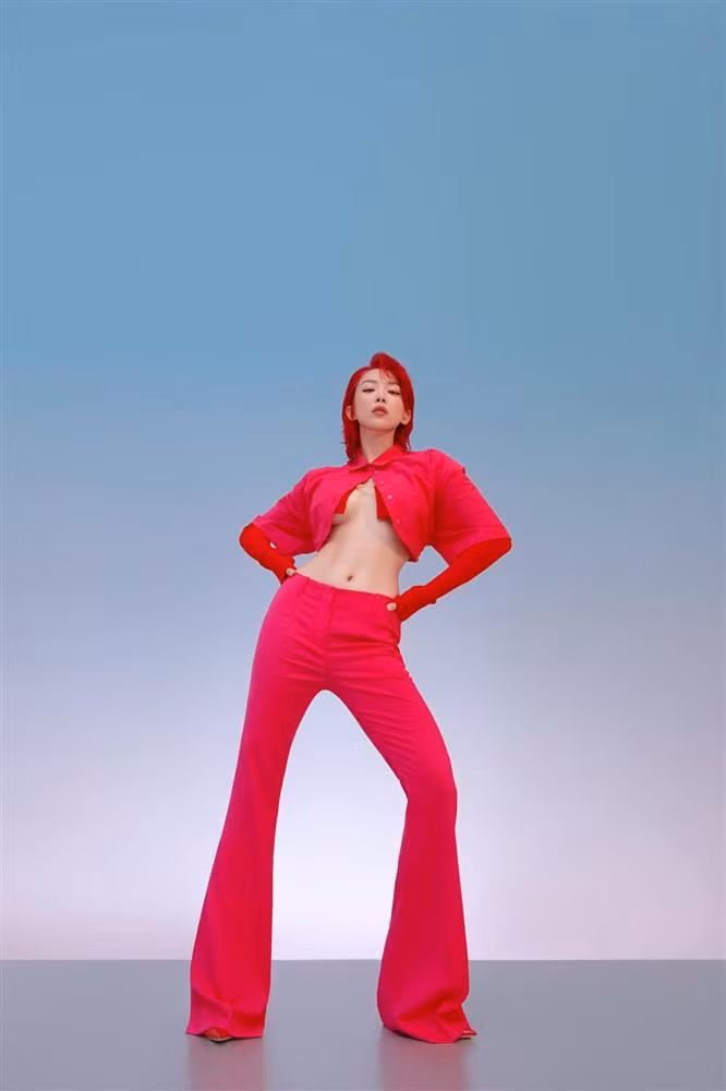 Set đồ nhuốm sắc hồng gồm áo sơ mi lửng khoác ngoài áo len móc cài và quần ống loe cộng thêm màu tóc màu đỏ khiến diện mạo của Tóc Tiên trở nên ''nóng rực''.