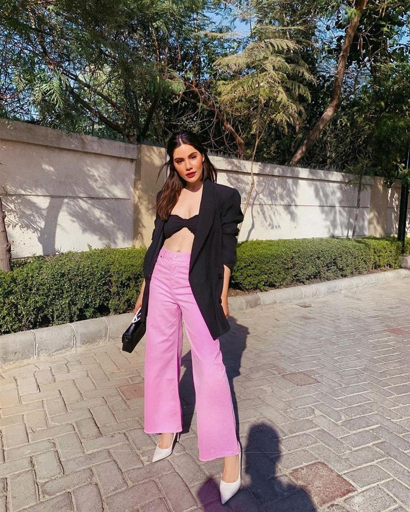 Quần ống loe hồng tím dịu mắt được fashion blogger Roshni Bhatia mix cùng áo ngực, khoác ngoài chiếc blazer ngoại cỡ màu đen. Giày cao gót mũi nhọn màu trắng giúp cân bằng bộ outfit của người đẹp.