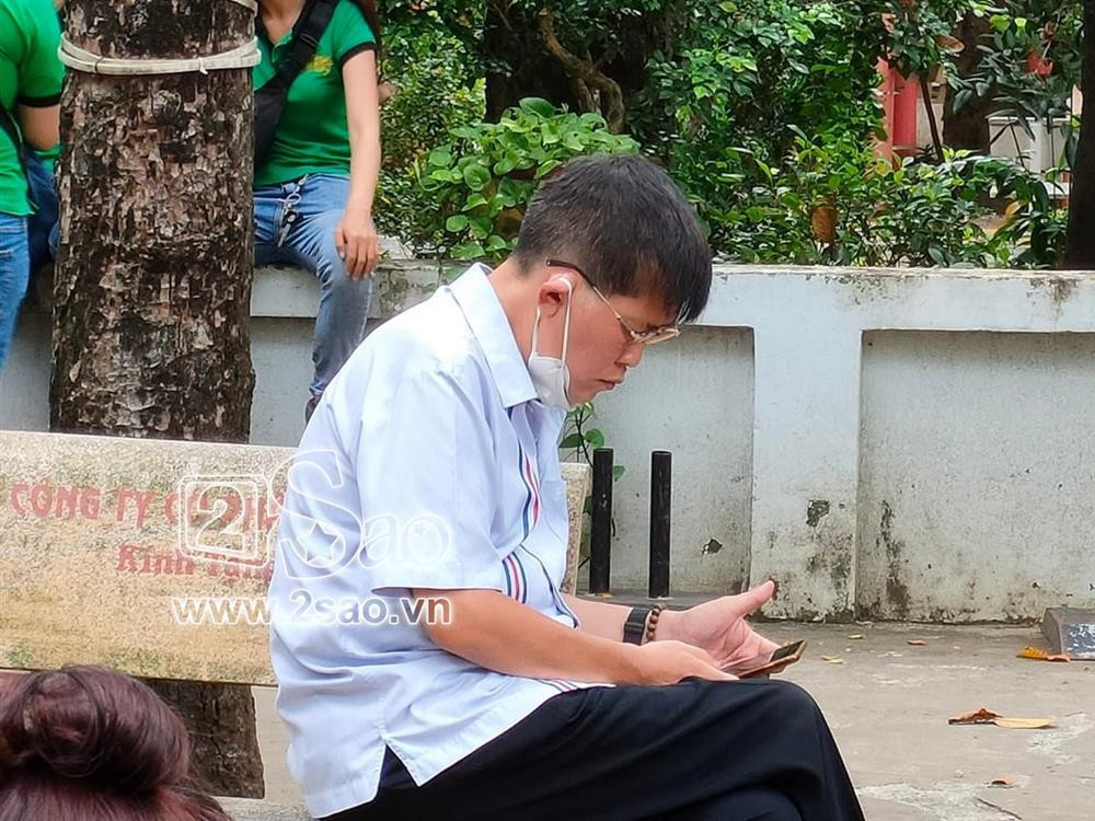 Phước Sang ngồi lặng một góc sân chùa bấm điện thoại khi tới tham dự lễ 49 ngày của Phi Nhung.