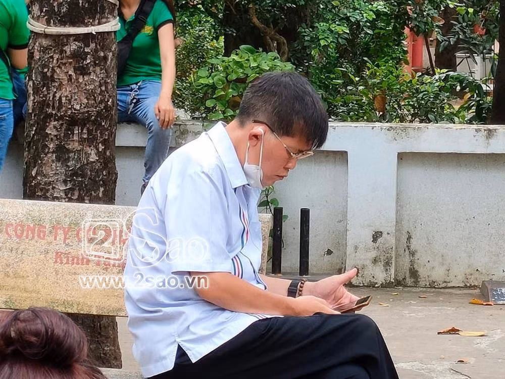 Phước Sang ngồi lặng một góc sân chùa bấm điện thoại khi tới tham dự lễ 49 ngày của Phi Nhung.