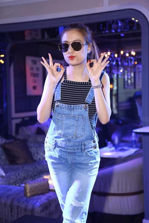 Hoàng Thùy Linh trở nên trẻ trung và xinh xắn hơn khi chọn quần jean yếm mặc cùng áo hai dây kẻ sọc nhỏ.