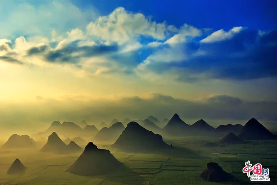 Núi đồi mấp mô giữa cánh đồng cải mênh mông tựa như chiếc nón úp giữa “biển vàng”. Màn sương sớm mờ ảo càng khiến cho khung cảnh Luoping trở nên lung linh, tựa như thiên đường.