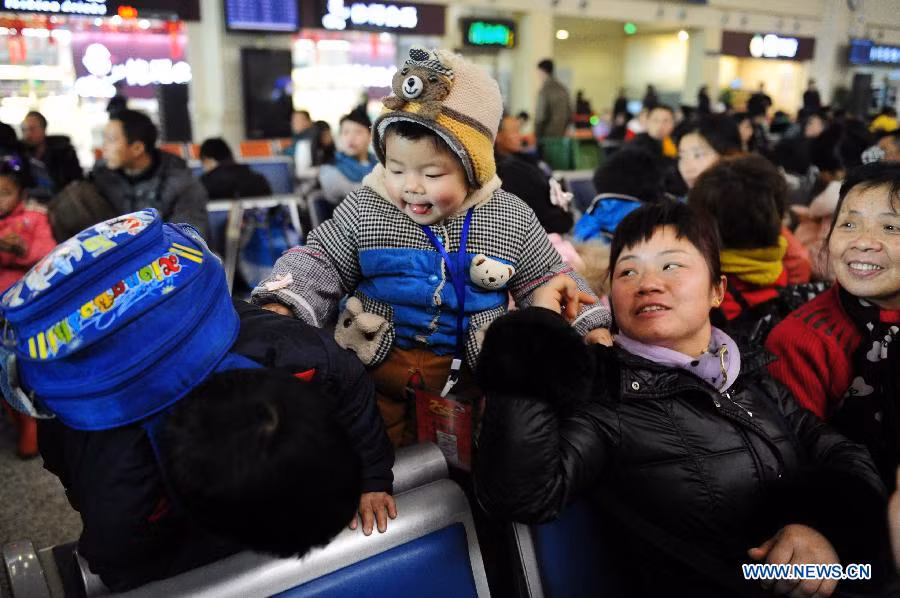 Bà mẹ 2 con Fu Chenyi, một công nhân nhập cư chơi đùa với con khi ngồi chờ tàu để về quê ăn tết tại ga Hán Khẩu ở thành phố Vũ Hán, thủ phủ của tỉnh Hồ Bắc.