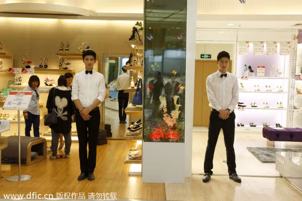 Hai người mẫu nam đang đứng trước cửa hàng giày dép tại trung tâm mua sắm.