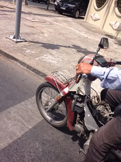 Chú cho xe đậu đúng vạch phân cách rồi từ từ bỏ xâu chuỗi xuống tay, lần từng hạt, từ tốn như không có chuyện gì... Ảnh: Trần Ngọc Ần.