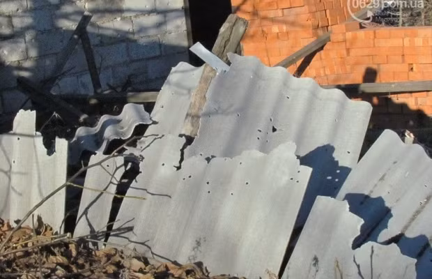 Các tấm lợp fibro xi măng dựng lên quanh ngôi nhà bị vỡ.