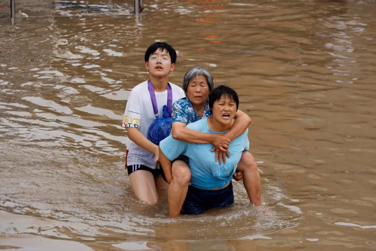 Người phụ nữ trẻ cõng một người phụ nữ lớn tuổi qua khu vực bị ngập nước ở Trịnh Châu, Hà Nam, Trung Quốc, ngày 23/7/2021.