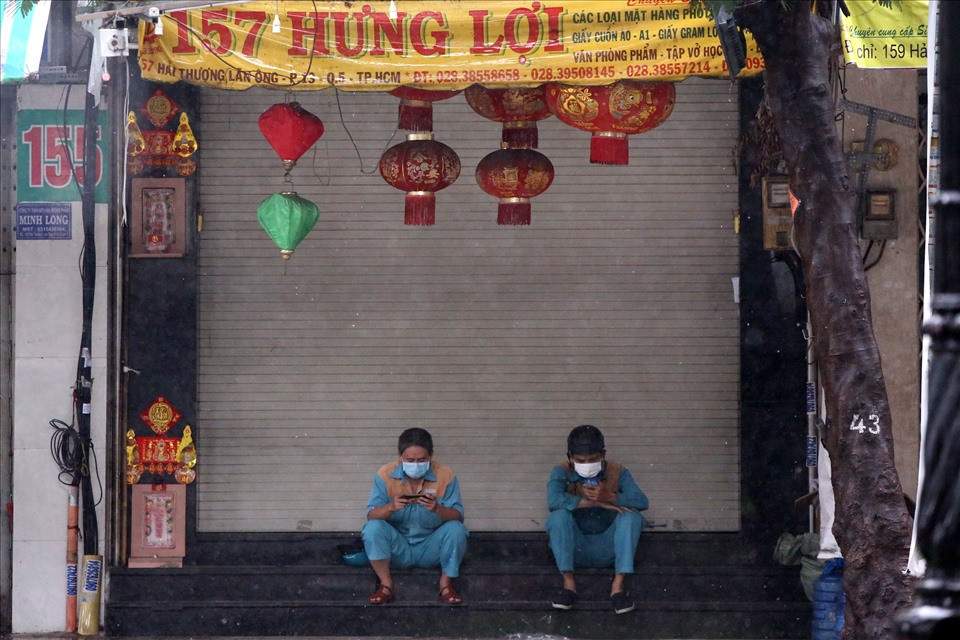 Hai nhân viên viễn thông trú mưa trước của một cửa hàng đang đóng cửa.